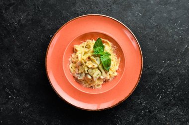 Tavuklu makarna, mantar, peynir ve fesleğen. İtalyan yemeği. Siyah taştan bir arka planda.