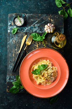 Tavuklu makarna, mantar, peynir ve fesleğen. İtalyan yemeği. Siyah taştan bir arka planda.
