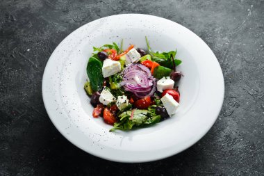 Sebzeli geleneksel Yunan salatası. Siyah taştan bir arka planda.