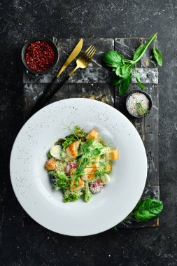 Geleneksel Sezar salatası ve tavuk. Siyah taştan bir arka planda.