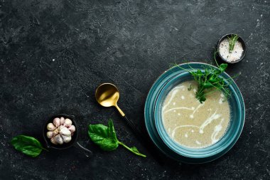 Kremalı ve hindiba soslu mantar kremalı çorba. Mavi bir tabakta. Siyah taştan bir arka planda.