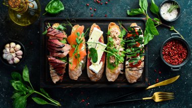 Ton balıklı, peynirli, jambonlu ve domatesli sandviç seti. Siyah taştan bir arka planda.