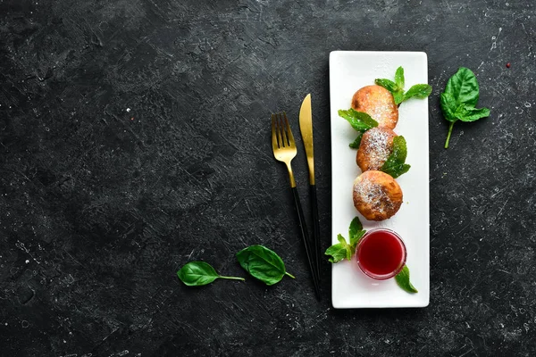 stock image Dessert. Cheese pancakes with raspberry sauce and powdered sugar. On a black stone background.