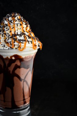 Plastik bardakta çikolatalı milkshake. Siyah bir arka planda. Metin için boş alan.