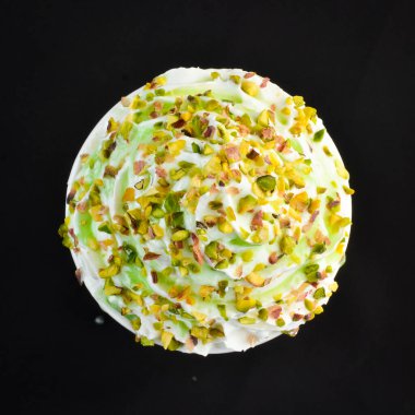 Fıstıklı kahve ve kremalı kağıt bardak. Siyah bir arka planda. Metin için boş alan.