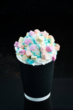 Şekerlemeli kahve ve kağıt bardakta krema. Siyah bir arka planda. Metin için boş alan.