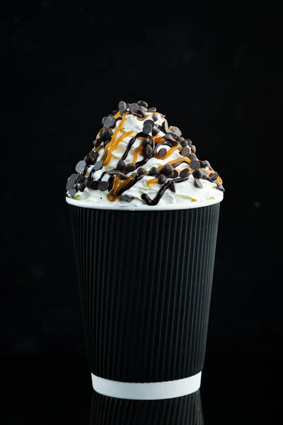 紙コップにキャラメルとクリームを入れたコーヒー 黒を背景に テキストのためのフリースペース — ストック写真