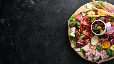 Aperatifler: peynir, jambon, salam, domuz pastırması, zeytin ve ahşap kapari. Üst Manzara. Metin için boş alan.