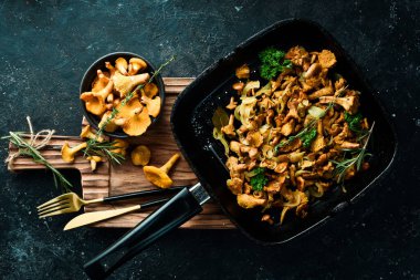 Mutfak masasındaki tavada soğan ve baharatla kızartılmış Chanterelle mantarları. Üst Manzara. Metin için boş alan.