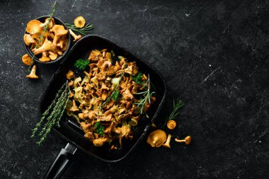 Mutfak masasındaki tavada soğan ve baharatla kızartılmış Chanterelle mantarları. Üst Manzara. Metin için boş alan.