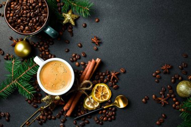 Masada bir fincan kahve ve yılbaşı süslemeleri. Üst görünüm, siyah arkaplan, bedava kopya alanı. Tatil.