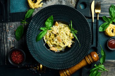 Pesto soslu makarna ve siyah kasede tavuk. Karanlık bir arkaplanda, yakın plan.