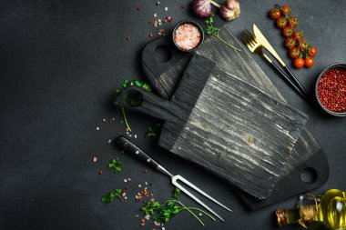 Mutfak tahtası ve mutfak ahşap aletleri mutfak masasında. Karanlık bir arka planda. Üst Manzara. Metin için boş alan.