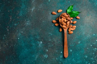 Tahta kaşıkta badem fıstığı. Sağlıklı atıştırmalıklar. Üst Manzara. Karanlık bir arka planda.