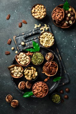 Fıstıklar, cevizler, bademler, fındıklar ve fındıklar ahşap kaselerde karıştırılmış. Üst Manzara. Karanlık bir arka planda.