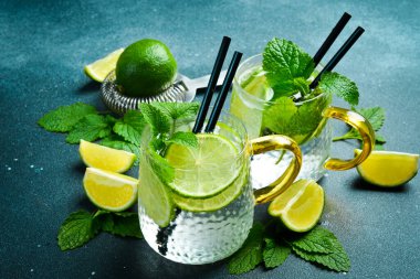 Bir bardak geleneksel mojito kokteyli, naneli ve limonlu. Koyu taştan bir masada..