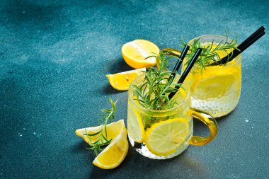 Limonlu limonata ve buzlu biberiye. Koyu taştan bir masada. İçkiler.