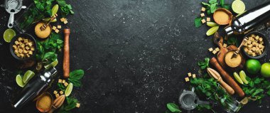 Mojito. Titretici, şeker, taze kireç ve tahta üzerinde nane. Siyah taştan bir arka planda. Üst görünüm.