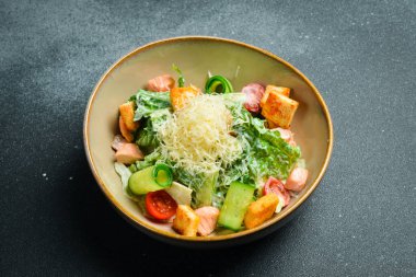 Klasik somonlu Sezar salatası. Siyah taştan bir arka planda. Bir tabakta, yakın plan..