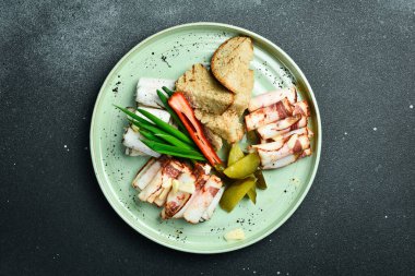 Kahverengi ekmek ve sebzeyle dilimlenmiş tuzlanmış domuz yağı. Geleneksel Ukrayna yemekleri. Tabakta. Restoran servisi. Kapatın. Karanlık bir taş arka planda.