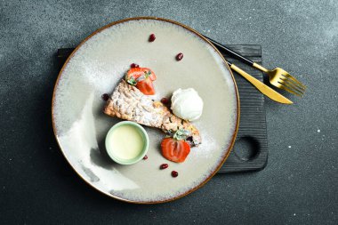 Bir kaşık dondurma ve kremayla birlikte bir parça haşhaşlı kek. Kapatın. Bir tabakta Siyah bir taşın arkasında.