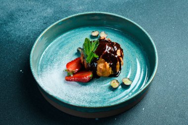 Çikolatalı ve çilekli kremalı pasta. Karanlık bir taş arka planda.