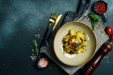 Domuz pastırması ve soğanlı ev yapımı patates kızartması. Siyah taştan bir arka planda. Metin için boş alan.