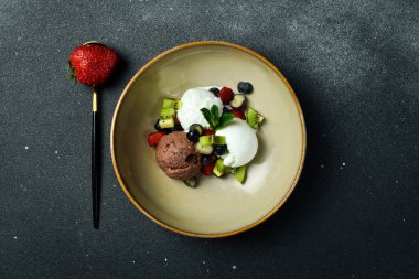 Tatlı. Çikolata ve meyveli vanilyalı dondurma. Siyah taştan bir arka planda. Metin için boş alan.