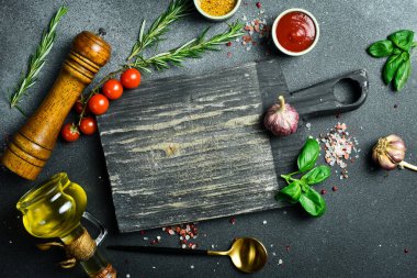 Tahta kesme tahtası ve baharatlar, siyah taş masada yemek için bitki. Menü, tarif modeli, metin için kopyalama alanı olan pankart arkaplanı.