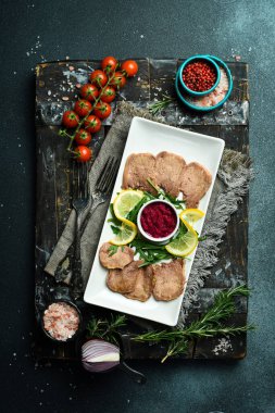 Limonlu ve pancar soslu haşlanmış dana dili. Koyu bir arkaplanda.