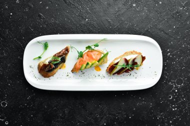 Avokado, domates ve etle bir set bruschetta. Antipasto soğuk atıştırmalıklar. Restoran menüsü. Beyaz bir tabakta.