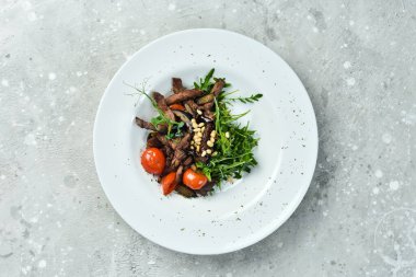 Dana etli taze salata: roka, dana eti, çam fıstığı ve patlıcan. Sağlıklı yiyecekler. Beyaz bir tabakta. Kırsal biçim.