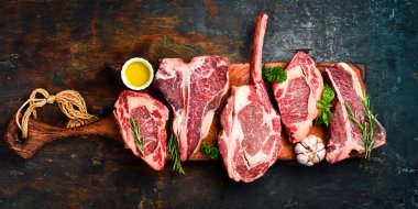 Tahtadaki ana biftekler: domahawk bifteği, Ribeye, T-bone ve Ossobuco. Izgara için biftek seti. Üst görünüm.