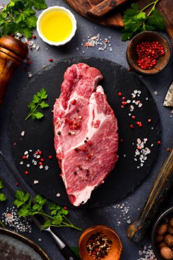 Çiğ domuz boyunlu, baharatlı ve ızgara biftek için otlu. Gri taştan bir arka planda.