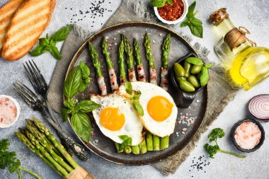 Faydalı bir kahvaltı. Kızarmış kuşkonmaz, pastırma ve kızarmış yumurta tabağı. Üst görünüm.