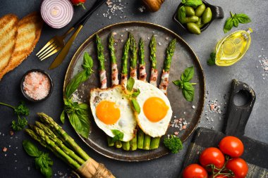 Kahvaltı: yeşil kuşkonmaz, tavuk yumurtası ve pastırma. Taş bir levhada, yakın plan..