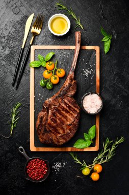 Kemiğe tuz, tereyağı ve biberle ızgara Tomahawk bifteği. Siyah bir arka planda Siyah Angus bifteği. Üst görünüm.