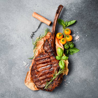 Kemiklerde ızgara biftek. Gri beton arka planda. Metin için boş alan. Üst görünüm.