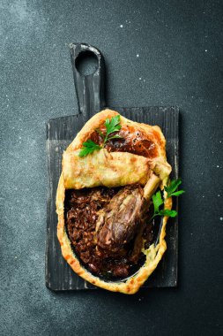 Fırında hindi budu, domates ve dolmalık biber. Geleneksel Türk yemeği. Siyah taştan bir arka planda.