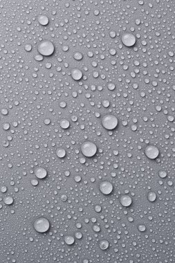 Soyut gri arka plana su damlıyor. Makro fotoğraf. Üst görünüm.