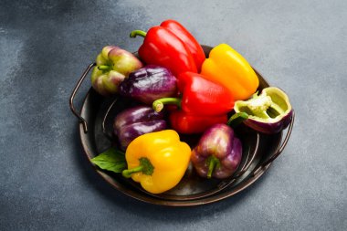 Kırmızı, mor ve sarı dolma biber. Metal tepside kırmızı biber. Metin için boş alan.