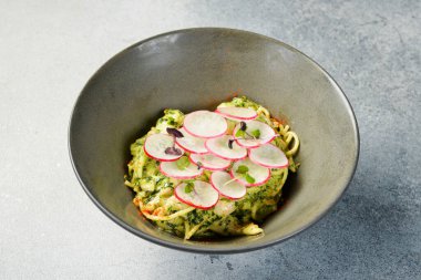 Peynirli İtalyan makarnası, pesto sosu ve turp. Tabakta. Üst görünüm.