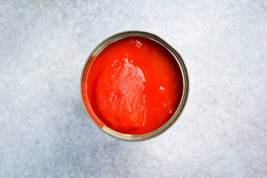 Metal bir kavanozda kırmızı domates turşusu. Yiyecek stokları. Gri beton arka planda.