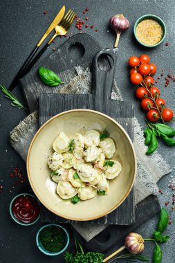 Etli geleneksel ravioli. Pelmeni tereyağı ve soğanlı bir tabakta. Tabakta. Restoran servisi. Kapatın. Karanlık bir taş arka planda.