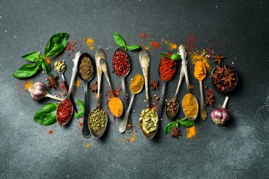 Antika kaşıklarda baharat ve bitkiler. Yemek pişirmek için çeşitli renklerde baharatlar. Siyah bir arkaplanda.