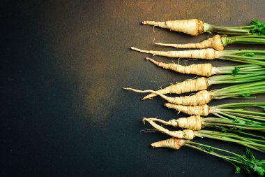 Taze maydanoz kökü, ve maydanoz yeşili, koyu arka planda, yakın plan, üst manzara.