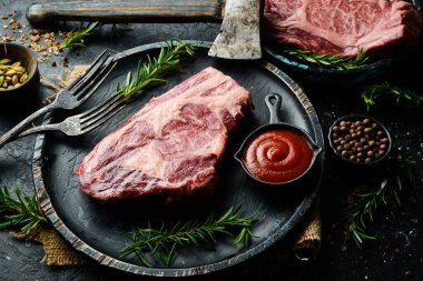 Siyah taşlı arka planda çatalı olan çiğ biftekli siyah Angus. Kırsal biçim.