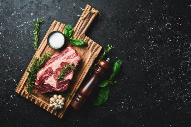 Tahta bir tahtanın üzerinde baharatlı, sulu, çiğ biftek. Metin için boş alan. Üst görünüm.