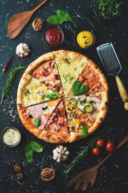 Pizza afişi. Siyah taşlı arka planda farklı pizza ve malzemeler var. Üst Manzara. Pizza arka planı.