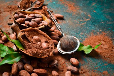 Tahta bir kasede kakao çekirdeği ve kakao tozu. Karanlık bir arka planda. Yan görünüm.